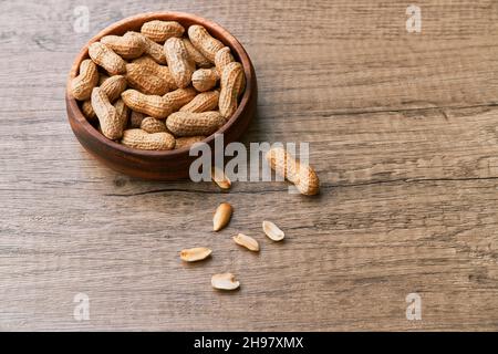 Immagine di un mazzo di arachidi in una ciotola su un tavolo di legno Foto Stock