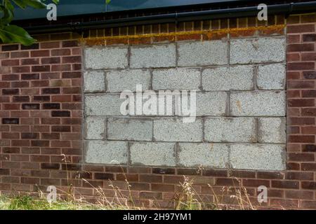 Spazio finestra in un muro di mattoni, bloccato con blocchi di cemento Foto Stock