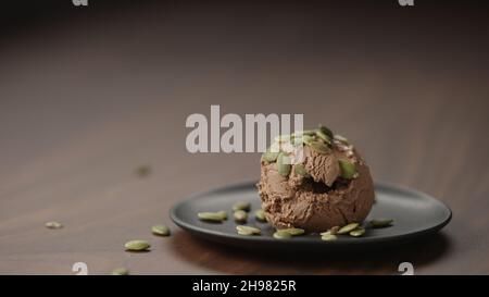 gelato al cioccolato con semi di zucca su piattino su tavola di legno, foto ampia Foto Stock