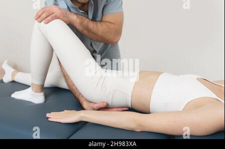 Sollievo dal dolore al ginocchio in clinica. Medico fisioterapista che fa il trattamento healing sulla gamba del paziente. Terapista che dà massaggio a gambe e vitelli. Osteopatia Foto Stock