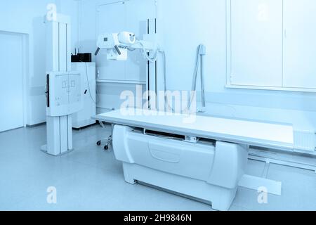 Reparto raggi X in ospedale moderno. Sala di radiologia con macchina di scansione con letto vuoto. Tecnico che regola una macchina a raggi X. Scansione torace, cuore Foto Stock