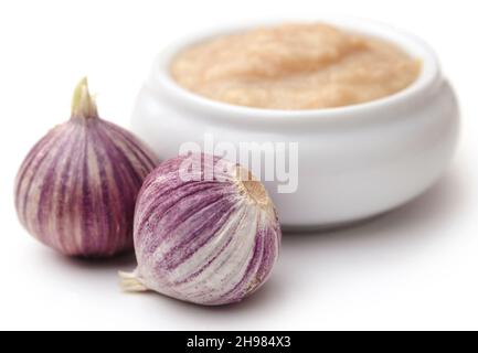 Solo o spicchio singolo aglio con pasta in un recipiente su sfondo bianco Foto Stock