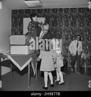 John Laing and Son Limited, Page Street, Mill Hill, Barnet, Londra, 15/12/1973. Un intrattenitore con un manichino ventriloquista che parla a due giovani ragazze durante la festa annuale di Natale per bambini tenuta dal Laing Sports Club presso gli uffici di Mill Hill di John Laing e Son Ltd. Il Laing Sports Club ha tenuto la sua festa annuale di Natale per bambini sabato 15 dicembre. Il partito era per 120 bambini sotto i 7 anni; i bambini più grandi hanno visto una pantomima di Cenerentola a Wembley. La festa per bambini presso gli uffici di Mill Hill ha visto giochi, un tè tradizionale e uno spettacolo di cartoni animati, seguito da una visita da Fatthe Foto Stock