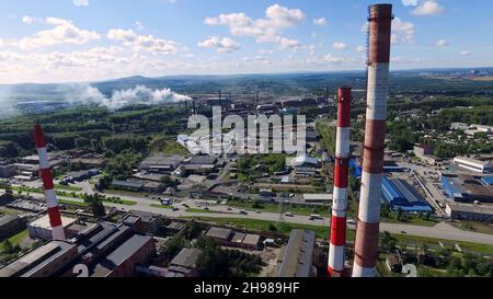 Vista panoramica dall'alto del panorama industriale dei tubi tecnologici e degli impianti. Riprese. Produzione industriale su sfondo di città e dis Foto Stock