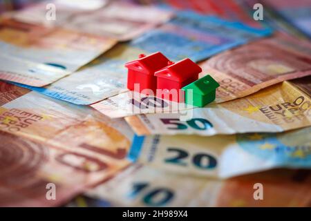 Tavolo coperto con banconote in euro con case in cima. Concetto di investimento immobiliare Foto Stock