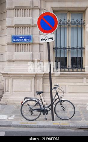 Bicicletta parcheggiata contro un cartello a Parigi Francia Foto Stock