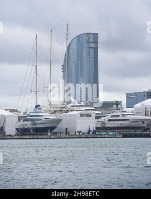 Barcellona, Spagna - 24 Nov, 2021: Superyacht e barche in barca a vela nel cantiere di Barcellona con l'hotel W sullo sfondo Foto Stock