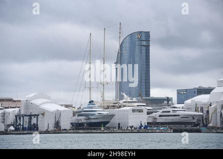 Barcellona, Spagna - 24 Nov, 2021: Superyacht e barche in barca a vela nel cantiere di Barcellona con l'hotel W sullo sfondo Foto Stock