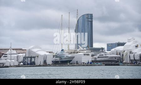 Barcellona, Spagna - 24 Nov, 2021: Superyacht e barche in barca a vela nel cantiere di Barcellona con l'hotel W sullo sfondo Foto Stock