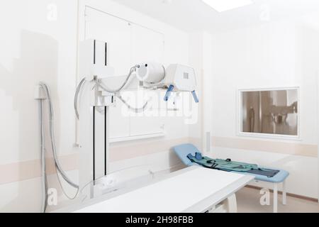 Reparto raggi X in ospedale moderno. Sala di radiologia con macchina di scansione con letto vuoto. Tecnico che regola una macchina a raggi X. Scansione torace, cuore Foto Stock