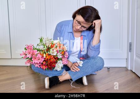 Triste turbata donna di mezza età con un bouquet di fiori Foto Stock