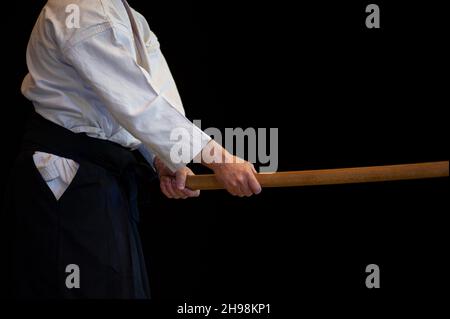 Aikido della cintura nera master durante una sessione di allenamento. Sfondo nero. Foto Stock