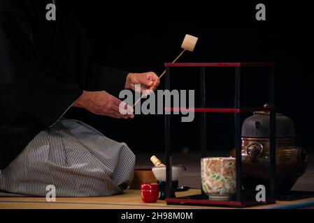 Maestro giapponese in kimono tradizionale, durante la cerimonia del tè. Sfondo nero. Foto Stock