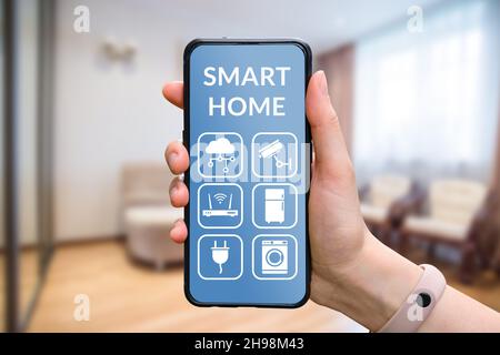 Concetto IoT o Internet delle cose. La persona controlla in modo intelligente l'applicazione sullo smartphone con le mani. Foto Stock