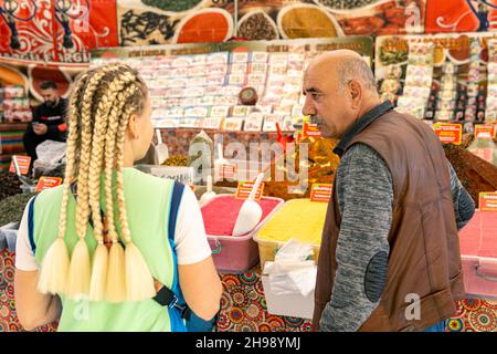 Kemer, Turchia - 08 novembre 2021: bazaar Merchant invita un turista a gustare il tè zenzero Foto Stock