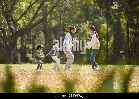 giovane famiglia asiatica con due bambini che si diverte a giocare all'aperto nel parco Foto Stock