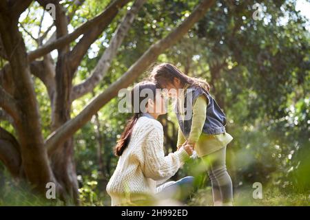 giovane madre asiatica e figlia godersi un buon tempo all'aperto nel parco della città Foto Stock