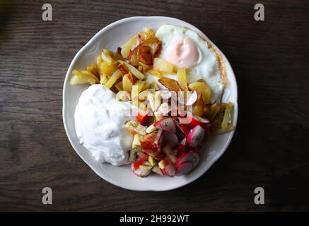 Insalata fresca, formaggio caserma e uova fritte su un piatto Foto Stock