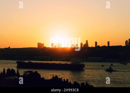 Tramonto dietro gli edifici di istanbul. Creazione di silhouette. La nave che attraversa il Bosforo. Foto Stock