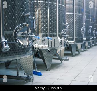 Vasche in acciaio inox per la fermentazione delle uve. Interno cantina, fuoco selettivo Foto Stock