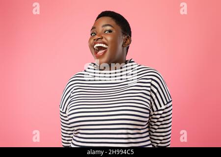 Allegra ragazza afroamericana di dimensioni più grandi Laughing su sfondo rosa Foto Stock