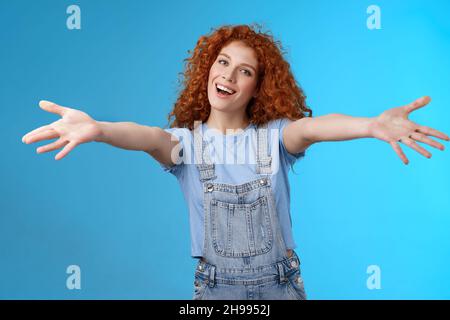 Amichevole allegra famiglia-orientata elegante affascinante redhead ragazza ricci-capelli estendere le braccia abbracci wanna coccole sorridente testa d'inclinazione tenero grin invitante Foto Stock