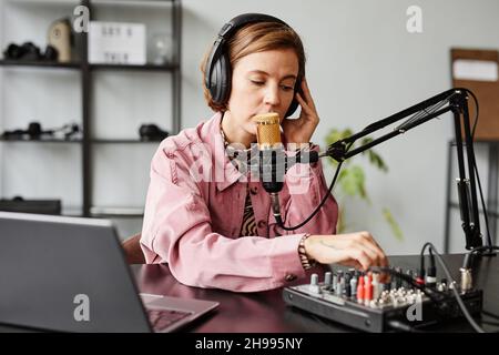 Ritratto di giovane donna che parla al microfono mentre registra podcast in studio Foto Stock