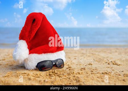 santa hat e occhiali da sole maschi sulla spiaggia di sabbia marina. Foto Stock