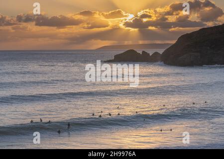 Surfers con un grande swell al tramonto sulla sempre popolare spiaggia di sabbia di Praa sulla costa sud della Cornovaglia Foto Stock