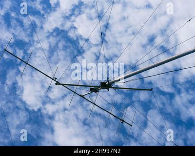 Antenna radio VHF con funi di supporto contro un cielo nuvoloso Foto Stock