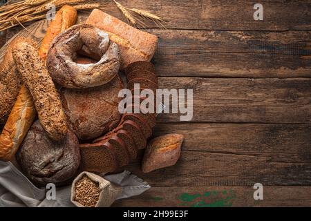 Pane tradizionale appena sfornato di vari tipi su un tavolo di legno. Vista dall'alto, spazio di copia. Foto Stock