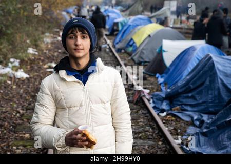 Dunkerque, Francia. 05 dicembre 2021. Un giovane migrante dalla regione curda dell'Iran ha visto tenere un pezzo di pane e una tazza di tè in un campo migrante improvvisato.ci sono stimati circa 800 migranti/rifugiati attualmente che soggiornano nella zona di Dunkerque nella Francia settentrionale. La maggior parte di loro sono in attesa delle loro opportunità di raggiungere il Regno Unito sia da gommoni gommoni o nascondersi in camion. Credit: SOPA Images Limited/Alamy Live News Foto Stock