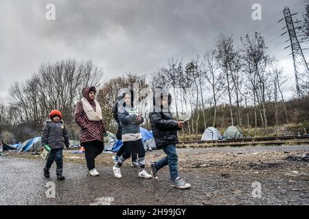 Dunkerque, Francia. 05 dicembre 2021. Una donna curda ha visto camminare con i bambini in un campo migrante improvvisato.ci sono stimati circa 800 migranti/rifugiati che attualmente soggiornano nella zona di Dunkerque nella Francia settentrionale. La maggior parte di loro sono in attesa delle loro opportunità di raggiungere il Regno Unito sia da gommoni gommoni o nascondersi in camion. (Foto di Geovien SO/SOPA Images/Sipa USA) Credit: Sipa USA/Alamy Live News Foto Stock