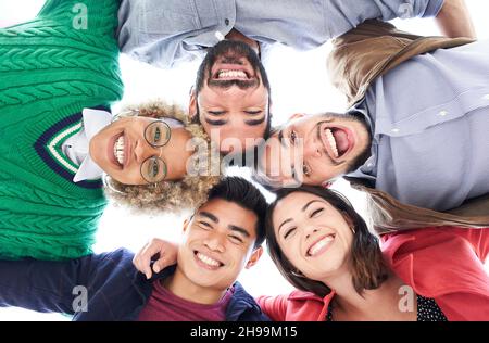 Gruppo multirazziale di amici che si divertono. Gruppo di persone in piedi in cerchio sorridendo guardando la fotocamera e ridendo. Concetto di amicizia. Foto Stock