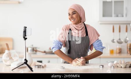 Culinary Vlog. Happy Islamic Woman Recording Video durante la cottura in cucina Foto Stock