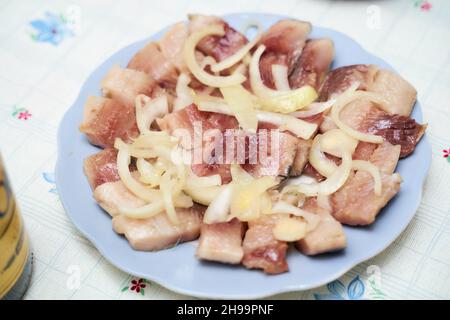 Aringhe tagliate a pezzi con cipolle su un piatto blu. Foto Stock