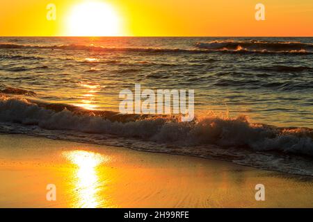 Il sole si avvicina all'orizzonte sopra le onde del Mar Baltico. Questo pittoresco fenomeno è stato osservato guardando dalla spiaggia di Kolobrzeg, po Foto Stock