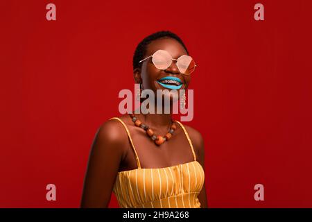 Felice attraente donna nera in occhiali da sole e vestito estivo Foto Stock