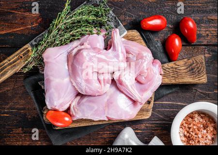 Zampe di lepre crude su un macellaio con timo. Sfondo di legno scuro. Vista dall'alto Foto Stock