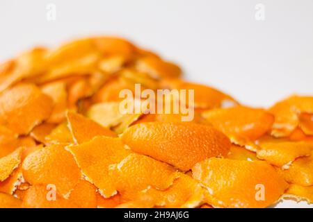 Sfondo di agrumi. Sfocatura sfondo Natale sfocato dalle bucce di arancio e mandarino su sfondo bianco. Molti piccoli pezzi di buccia secca. Foto Stock