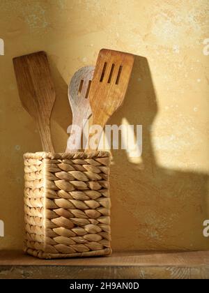 utensili da cucina in legno su ripiano su sfondo giallo Foto Stock