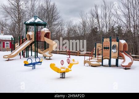 Un parco giochi vuoto coperto di neve a Speculator, NY USA all'inizio dell'inverno Foto Stock