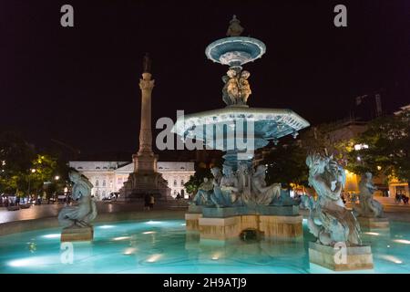 Vista notturna della fontana barocca e della colonna di Pedro IV nel centro di Piazza Rossio, Lisbona, Portogallo Foto Stock