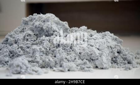 Primo piano di una manciata di polvere. Tutta la polvere dell'aspirapolvere è estratta con le mani nei guanti. Materiale grigio riciclato sul tavolo. Foto Stock