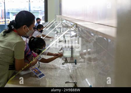 6 dicembre 2021: Un insegnante assiste gli studenti mentre si lavano le mani prima di frequentare lezioni di persona in una scuola elementare a Makati City, Metro Manila, Filippine. 6 dicembre 2021. Circa 28 scuole nella capitale filippina hanno iniziato a condurre classi limitate faccia a faccia con rigorosi protocolli sanitari per prevenire la diffusione di COVID-19. (Credit Image: © Basilio Sepe/ZUMA Press Wire) Foto Stock