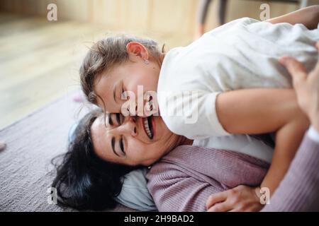 Piccola ragazza felice con nonna anziana in casa, giocando sul pavimento. Foto Stock