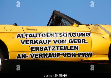 Cartello pubblicitario su un'auto distrutta in un cantiere. Germania, Europa Foto Stock