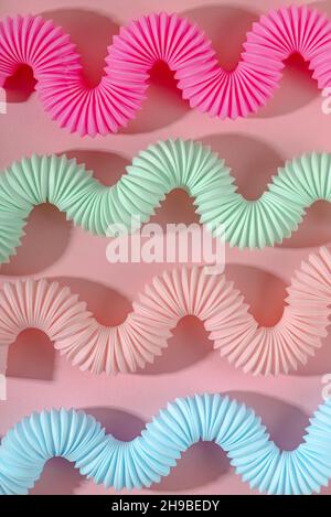 Giocattolo curvo rosa blu menta antistress pop tube con ombra su sfondo rosa. Giocattolo per bambini luminoso. Sfondo Foto Stock