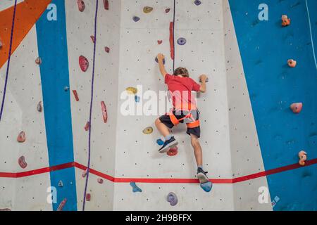 Ragazzo al muro di arrampicata senza casco, pericolo al muro di arrampicata Foto Stock