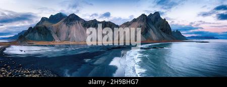 Vestrahorn montagna panorama. Drone ad angolo alto girato attraverso la spiaggia nera e dune di sabbia al tramonto. Penisola di Stokksnes, Islanda sud-orientale Foto Stock